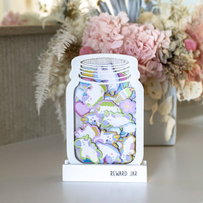 Decorative 'Reward Jar' with colorful designs on a white stand, with flowers in the background.